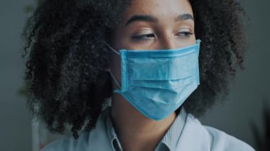 Hasta kadın öğrenci kıvırcık Afrikalı hasta. Coronavirüs enfeksiyonundan korunmak için tıbbi maske takıyor. Ağız ve burun tıkanıklığını her gün kapatıyor.