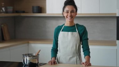 Güzel Arap fırıncısı aşçı aşçı ev hanımı etnik vejetaryen kadın modern mutfakta poz veren tatmin olmuş İspanyol kadın anne çapraz kollu aile yemeği hazırlıyor.
