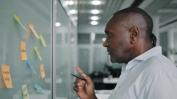 非洲商人执行内容经理制定战略计划管理公司工作任务阅读粘贴在黑板上的贴纸写想法项目要点备忘录策划目标头脑风暴 — 图库视频影像
