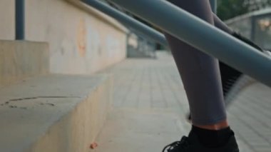 Kapalı bayan atletik bacaklar sporcu spor koşucusu spor ayakkabılı koşucu stadyumdaki spor salonunun merdivenlerini tırmanıyor yavaş yavaş aktif kadın dinamiklerini çalıştırıyor açık havada merdiven sporu yapıyor.