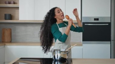 Aktif kadın şarkıcı, oyuncu dansçı genç bekar duygusal kadın bin yıllık anne Arap bayan ritmi ev mutfağında müzik eşliğinde şarkı söylüyor karaoke partisi yapıyor özgürce yemek pişiriyor.