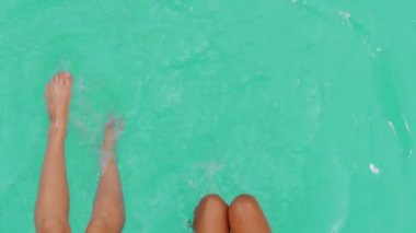 İki çift güneş yanığı, ince bacaklar güzel çıplak kadın vücudu yüzme havuzunda su sıçratan genç kızlar lüks bir tatil köyünde ayaklarını sallayan kadınlar.