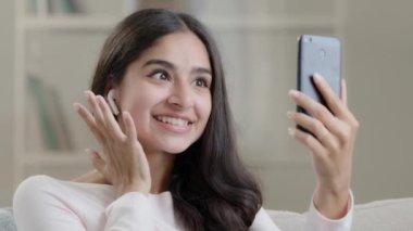 Güzel Arap ortadoğulu genç kız cep telefonlu kulaklık takıyor. Mobil kamera önünde konuşuyor. Sosyal medya yayını yapıyor.