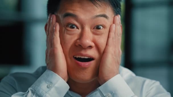 肯定的な感情的なアジア系韓国人男性ビジネスマン40代男性従業員手で顔を保持幸福感勝利良いショックは喜びを口を開きますすごい反応プロの成功キャリア成長勝利 — ストック動画