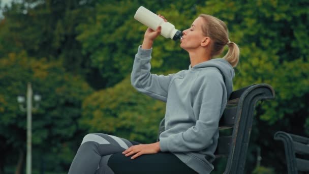 脱水女性スポーツ選手の女の子疲れたランナージョガー喉の渇き市内の公園でスポーツ演習後新鮮な冷たい水を飲む健康的なスポーツ栄養リフレッシュ健康管理体水分補給 — ストック動画