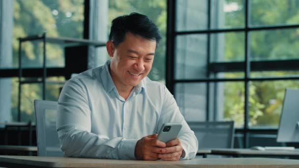 男性の肖像アジアの中国人男性起業家オフィスで働く現代のガジェット携帯電話の画面検索情報をオンラインで使用スマートフォンアプリ技術5GのWi Fiオンライン通信 — ストック動画