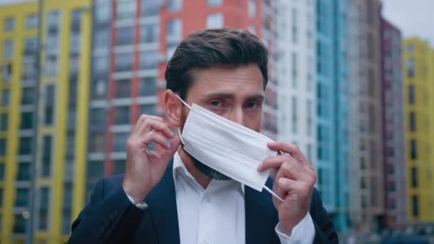 顔のマスクを身に着けているビジネスマンのクローズアップ肖像マスクを身に着けている人は 都市の通りで働く隔離措置に従ってくださいコロナウイルス感染からの個人的な保護医療概念 — ストック動画