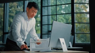 Asyalı etnik adam kıdemli Koreli Japon işadamı kağıt döküman kontrolü iş raporu ekran bilgi projesi verilerine bak bilgisayar analizi finansal belgeler