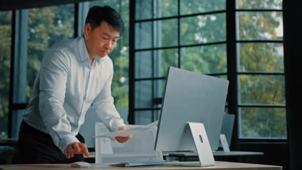 亚洲裔韩国人资深韩国商人专业工作与纸质文件核对业务报告在计算机分析财务文件中查看筛选搜索信息项目数据 — 图库视频影像