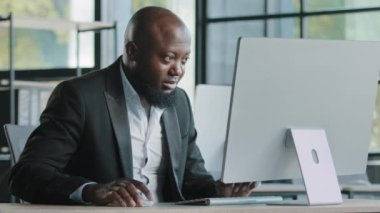 Profesyonel erkek işçi Afro-Amerikan 40 'lı yılların iş adamı milenyum etnik erkek pazarlamacısı modern ofis kodlama şirketinin iş programında kişisel bilgisayarında kişisel proje çalışması geliştiriyor.