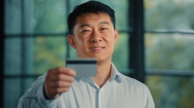 Asyalı, Japon, erkek, işadamı, bankacılık hizmetlerinin yatırımcısı, internet siparişi için limitsiz depozito ile birlikte online ticari alışverişler için kredi kartı tutuyor.