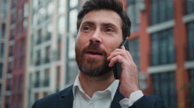 İş adamı mutlu Kafkas menajeri 30 'lu yaşlardaki erkek müşterisi şehir merkezindeki akıllı telefon durağından cep telefonu konuşmalarını arıyor.