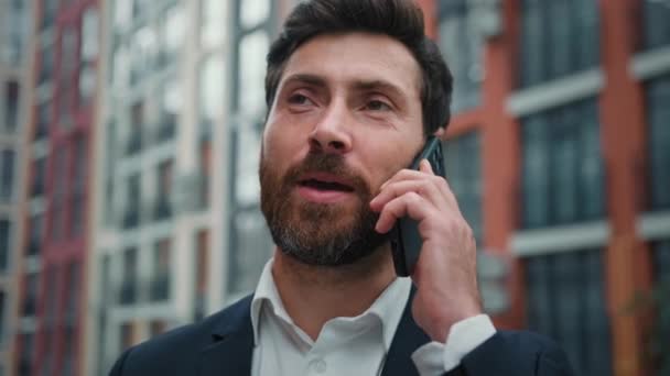 ビジネスマン幸せな白人マネージャー30代男性顧客は ダウンタウンの街の無線通信予約オンラインでスマートフォンスタンドで携帯電話の話を呼び出します遠隔インタビューリモート会話 — ストック動画