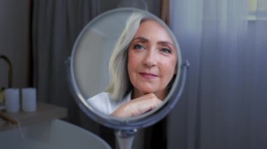 Gülümseyen kadın yüzü. 50 'li yaşlarda orta yaşlı, olgun bir kadın. Yüz derisinden zevk alıyor. Yaşlı kuru cilt güzellik prosedürleri kozmetik anti yaş estetik cerrahisi