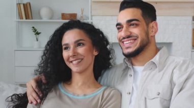 Hintli çok ırklı çift, etnik evli aile, sakallı erkek, etnik kadın, karı koca kucaklaşıp kucaklaşıyorlar. Kanepede oturup birbirlerine sarılıyorlar. Mutlu romantik bir birliktelik, televizyon izliyorlar.