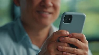 Bilinmeyen Asyalı işadamı, modern kullanıcı kıdemli girişimci el altında telefon araması internet bilgileri için cep telefonu uygulamaları Wi-5-G bağlantısı kullanarak akıllı telefondan mesajlar gönderiyor.