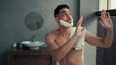 Banyoda yüzünde tıraş köpüğü jeliyle dans eden komik, çıplak İspanyol adam. Aptal, mutlu, kaygısız Hintli, sakallı, sakallı, erkek, traş olmadan önce.