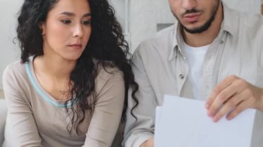 Çok ırklı etnik kökenli Hintli Latin kökenli, hayal kırıklığına uğramış, kağıt okuyan evli çift, yüksek ipotek kredisinin banka kredisinin reddedilmesinden olumsuz not aldığını vurguladı.