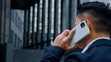 Tanımlanamayan Asyalı resmi takım elbiseli bir adam şehirde dikilip akıllı telefon konuşmaları yapıyor. Patron, girişimci işadamı ve iş adamı dışarıda cep telefonu konuşmaları yapıyor.