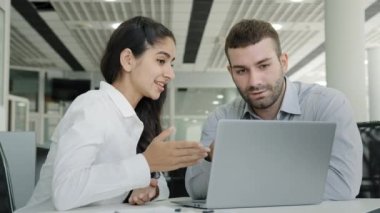 Ofiste oturan iş arkadaşları dizüstü bilgisayarda sunum yapan genç iş kadını müşterilerine iyi bir iş adamı liderinin raporları incelediğini ve kadın ve erkeğin ortak proje konseptini tartıştığını söylüyor.