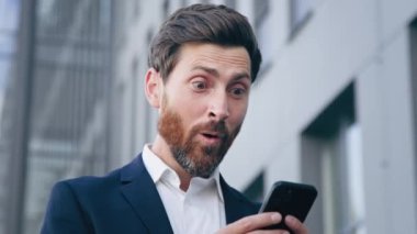 Yakın plan şaşkın adam cep telefonundan e-posta bildirimi okuyor mutlu haberler alıyor duygusal iş adamı online bahsi kazanıyor kumarhane kârlı bir iş teklifi alıyor
