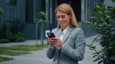 Mutlu ilham verici genç bir kadın cep telefonuyla dışarıda duruyor e-posta alıyor iyi haberler okuyor gülümseyen iş kadını mesajlar yazıyor sosyal ağların akıllı telefondan karlı teklifler aldığını kontrol ediyor.
