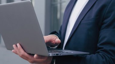 Yakın plan bilgisayarda yazan başarılı beyaz tenli yakışıklı işadamı dışarıda kameraya bakıyor gülümseyen erkek müşteri online mağazada sipariş veriyor e-posta iş portrelerini kontrol ediyor.