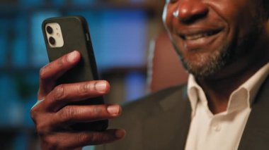 Telefonu elinde tutan adamın e-postası iyi haber okuyor gülümseyen iş adamı sosyal ağlara göz atıyor internetteki siparişi onaylıyor cep telefonuyla internet üzerinden video izleyerek.