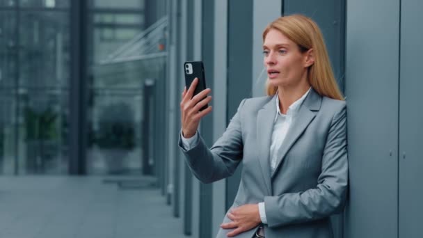 電話でウェブカメラを使用して屋外チャットオンライン会議に立っているビジネスマン女性ビデオチャットを介してクライアントにスマートフォンの話にカメラでビジネスビデオ通話リモート会話に答えるアジアの女性 — ストック動画