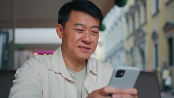 特写镜头快乐的亚洲男人拿着手机浏览社交网络男性游客订票用智能手机发邮件在网上聊天中交流购买网上商店 — 图库视频影像