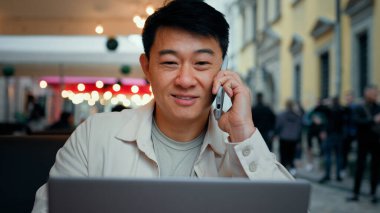 Telefonla konuşan adam dizüstü bilgisayar ekranlı erkek turist müşterisine bakıyor. İnternet işadamı serbest internet üzerinden bilet alıyor. Telefon kullanarak iş konularını tartışıyor.