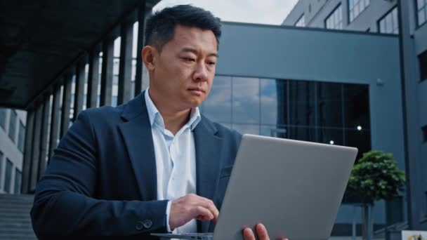 アジア系中国人40代中高年ビジネスマン弁護士フリーランスの投資家起業家都市の屋外にノートパソコンを入力します — ストック動画