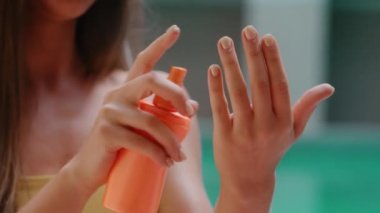 Yakın plan kadın elleri antiseptik sprey sürüyor. Bir şişe güneş kremi nemlendirici. Güneş kremi sürerken kadın avuçlarını ovalıyor.