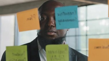 Afrika kökenli Amerikalı orta yaşlı uzman işadamı işadamı patron işadamı modern ofiste cam duvarlı, etnik insan işçisi çıkartmaları okuyarak yönetim sürecini organize ediyor.