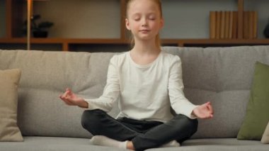 Şirin, sağlıklı, küçük bir kız çocuğu nilüfer çiçeğiyle rahatlamış rahat bir şekilde koltuğa oturmuş, evde meditasyon yapıyor güzel, küçük kız çocuğu yoga yapıyor, nefes egzersizi yapıyor, gözleri kapalı Zen ahengi hissediyorum.