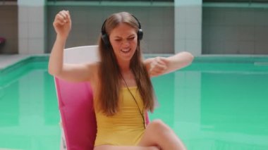 Kafkasyalı güzel sarışın turist kız. Kulaklıklı. Pop müzik en sevdiği şarkı. Lüks otel spa havuzunun yanında.
