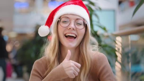 幸せなダンスを閉じる30代白人女性を身に着けている赤いサンタクリスマス帽子キャップと眼鏡陽気な女の子のダンス親指を示す素晴らしい完璧なサインお祝い新年割引お祝いムード — ストック動画