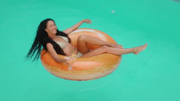 穿着比基尼泳衣穿着迷人的晒黑了的卷曲女日光浴躺在酒店游泳池里 年轻性感的西班牙女人在充气救生圈边游泳 喝着鸡尾酒 感觉自由享受夏天的热假期 — 图库视频影像