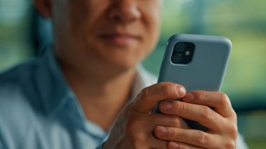 Bilinmeyen Asyalı işadamı, modern kullanıcı kıdemli girişimci el altında telefon araması internet bilgileri için cep telefonu uygulamaları Wi-5-G bağlantısı kullanarak akıllı telefondan mesajlar gönderiyor.