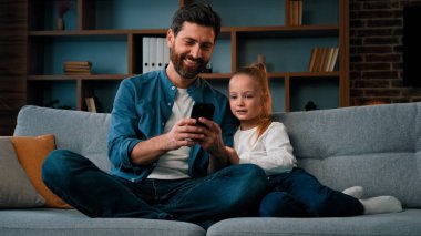 Mutlu aile kızı ve bekar baba modern aletlere bakın akıllı telefon videoları online internet iletişim kafkasyalı baba kızına cep telefonu ebeveyn kontrolünü kullanmayı öğretiyor.