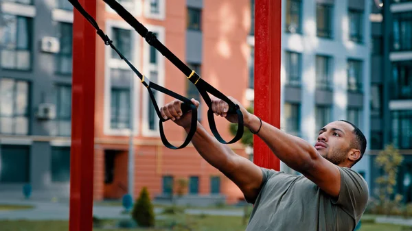 筋肉運動強力なラテンアメリカの男性のボディビルダースポーツマンは 都市のスポーツグラウンドで屋外ストレッチワークアウトを使用していますTrxストラップアクティブ健康的な生活とプルアップ運動 — ストック写真