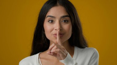 Stüdyo sarı arka planda kadın portresi. 20 'li yaşlarda. Kadın etnik kız. Sessiz hareket işareti.