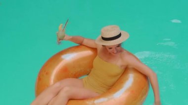 Güzel sarışın kadın bronz tenli gezgin mayosu şişme denizde mavi suyla yüzüyor ya da lüks bir otelde yüzüyor yaz tatili egzotik tatil beldesi turizmi içiyor.