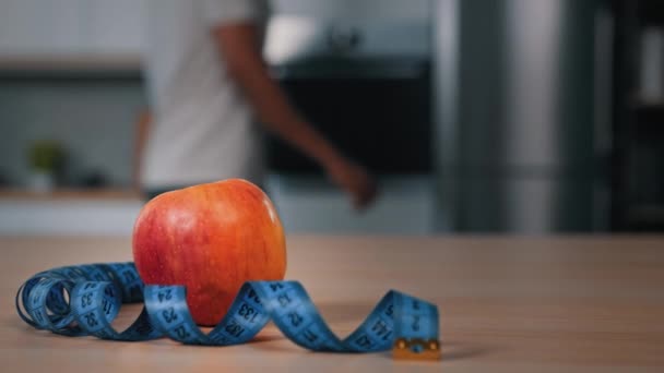 Red Apple Tape Measure Kitchen Table Foreground Blurred African Man — Stock Video