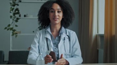 Afrikalı doktor, etnik kadın, stajyer doktor, eczacı, ilaç şişesi tutuyor. Damlatan ilaçların antibiyotik karışımı için anestetik ilaç reklamı öneriyor.
