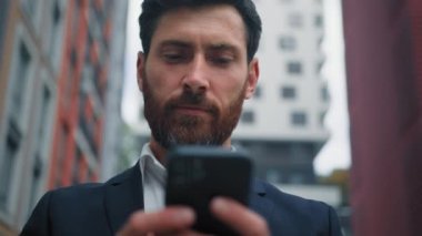 Erkek portresi işadamı serbest çalışan 30 'lu yaşlardaki Kafkasyalı yönetici cep telefonundan mesaj yolluyor medya içeriğini okuyor modern teknoloji kavramı için şehir wi-fi 5g interneti kullanıyor