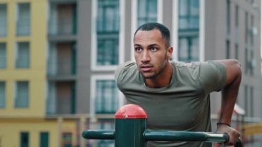 Erkek profesyonel vücut geliştirici güçlü Afrikalı Latin erkek sporcu iyi fiziksel formda erkek sporcu paralel barlarda şınav çekip şehir spor sahasında spor egzersizleri yapıyor.