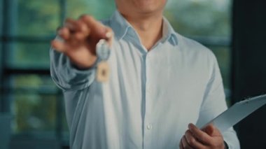 Emlak temsilcisi bankacı işadamı, yeni ev reklamındaki anahtar demetinde ev sahipleri için ev ipoteği, ev sahipleri için iş merkezi binasında konaklama imkanı sunuyor.