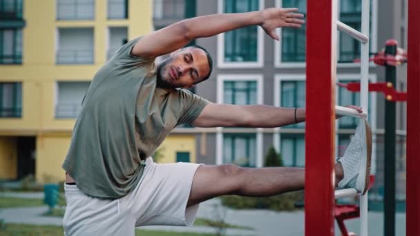 強力なラテンアメリカのスポーツマンのスポーツマンの男は 健康的な体の筋肉のための柔軟なストレッチ運動上の壁のバーに傾斜サイドベンド位置に立つ健康とスポーツの概念 — ストック動画