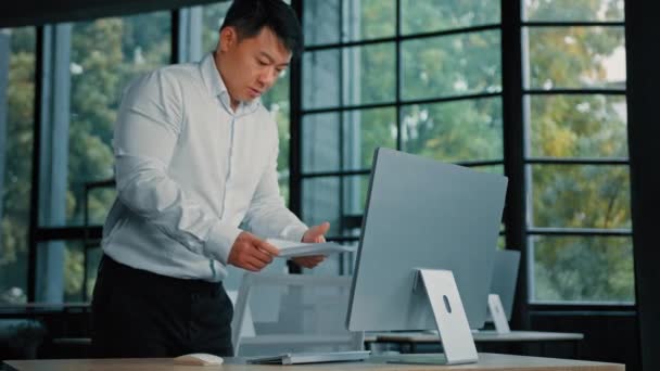 忙碌的亚洲中年韩国华裔商人专业人员检查计算机数据库信息工作与纸质文件财务报告管理公司文书工作 — 图库视频影像